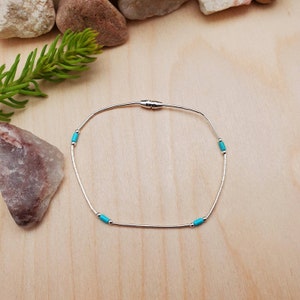 May include: A silver bracelet with turquoise beads. The bracelet has a magnetic clasp.