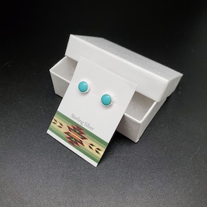 May include: A pair of turquoise and sterling silver stud earrings in a white box. The box has a card inside that says "Sterling Silver".