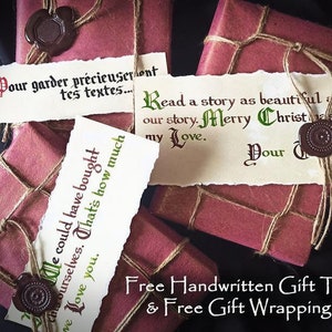 May include: Two red gift boxes wrapped in twine and sealed with wax. The boxes have handwritten gift tags with the text "Pour garder pr&eacute;cieuseront tes textes..." and "Read a story as beautiful as our story. Merry Christmas, my Love. Your ".