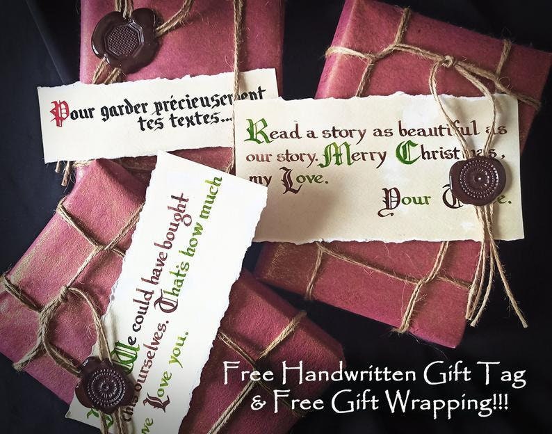 May include: Two red gift boxes wrapped in twine and sealed with wax. The boxes have handwritten gift tags with the text "Pour garder pr&eacute;cieuseront tes textes..." and "Read a story as beautiful as our story. Merry Christmas, my Love. Your ".