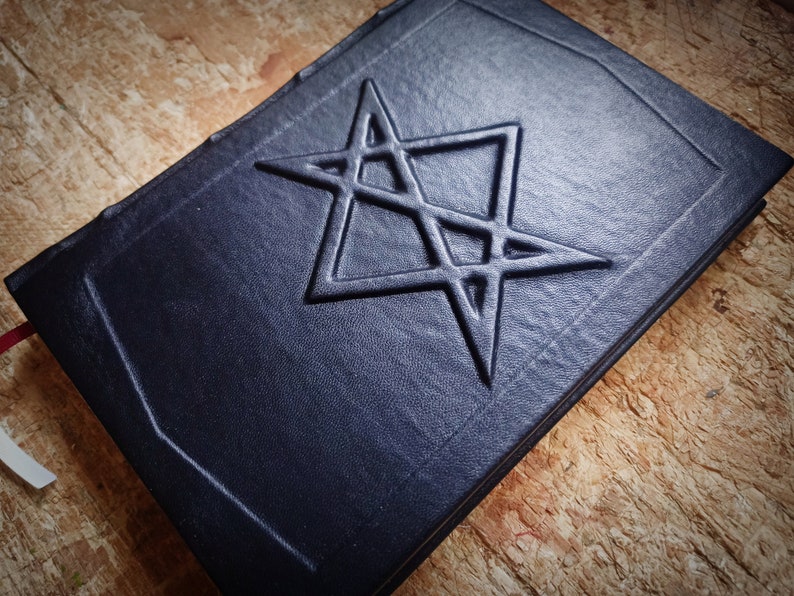 Puede incluir: Un diario de cuero azul oscuro con una estrella de cinco puntas en relieve en la portada.