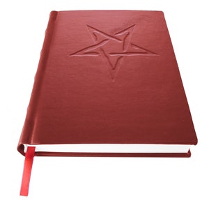 May include: A closed red leather-bound journal with a five-pointed star embossed on the front cover. The journal has a red ribbon bookmark.