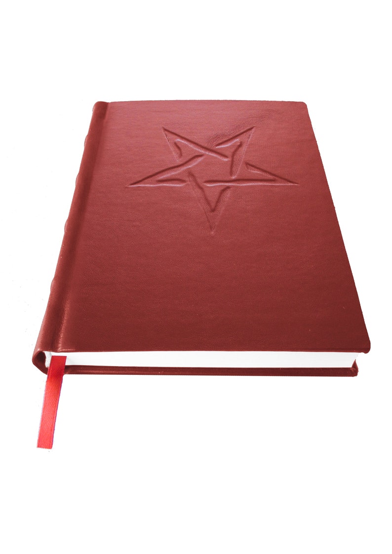 May include: A closed red leather-bound journal with a five-pointed star embossed on the front cover. The journal has a red ribbon bookmark.