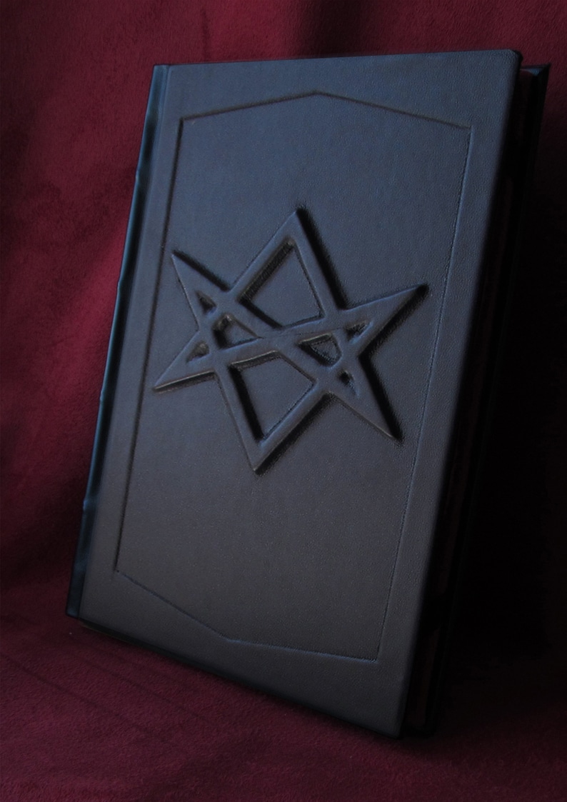 Puede incluir: Un libro encuadernado en cuero negro con un dise&ntilde;o de estrella de cinco puntas en relieve en la portada.