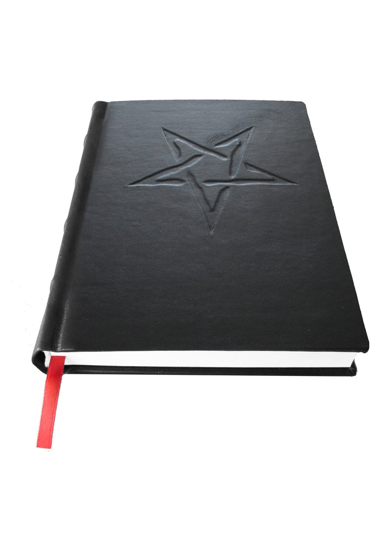 May include: A black leather-bound journal with a red ribbon bookmark. The front cover features an embossed pentagram.