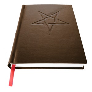 May include: A brown leather-bound journal with a five-pointed star embossed on the front cover. The journal has a red ribbon bookmark.