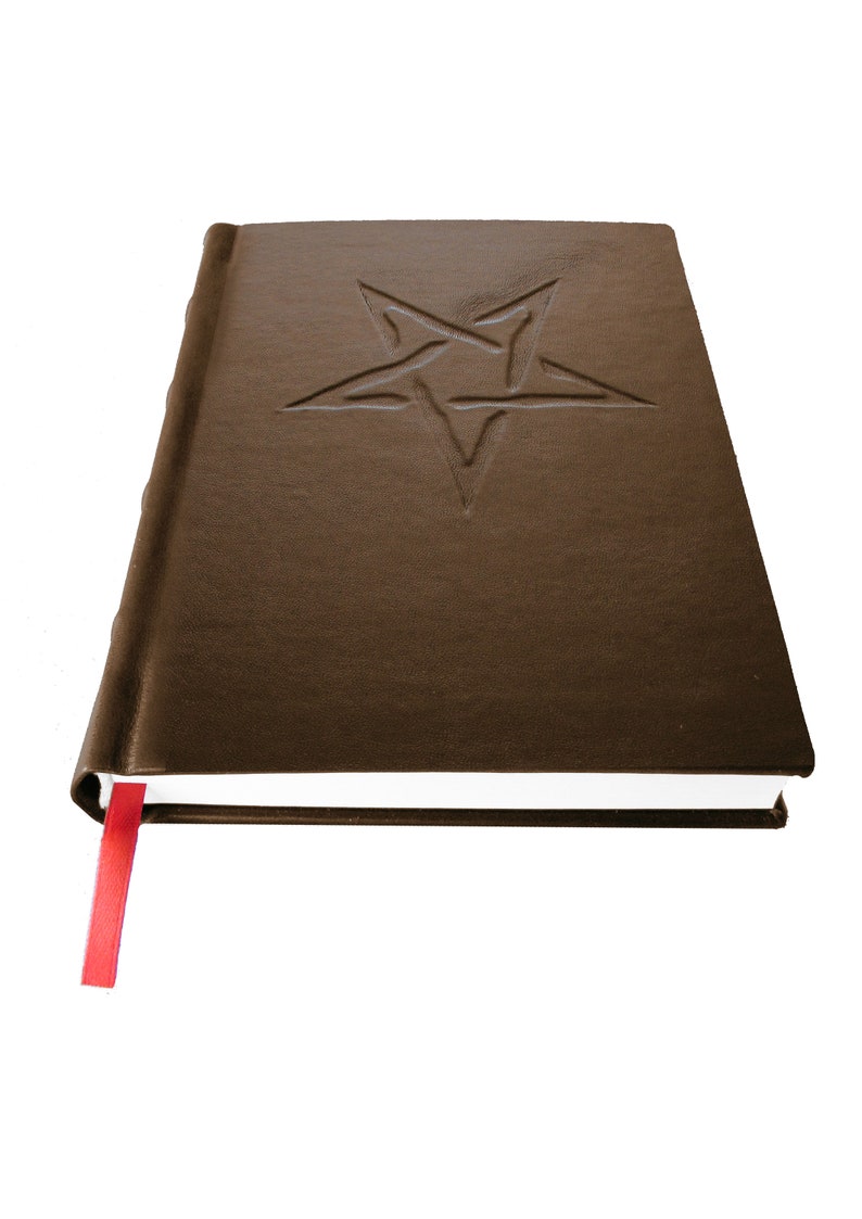 May include: A brown leather-bound journal with a five-pointed star embossed on the front cover. The journal has a red ribbon bookmark.