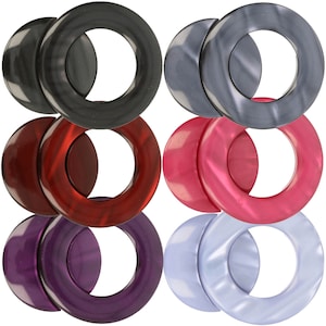 Puede incluir: Seis pares de anillos de cortina decorativos en varios colores, incluyendo negro, rojo, morado y azul. Cada anillo está hecho de un material liso y brillante y tiene una forma circular con un agujero en el centro.