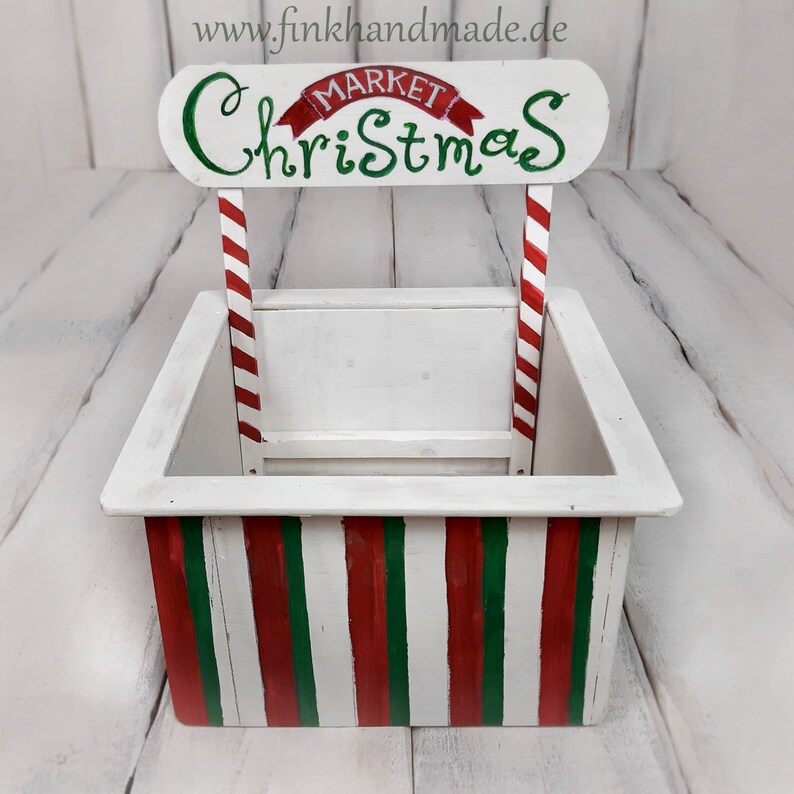 Puede incluir: Puesto de mercado navide&ntilde;o de madera blanca con rayas de bast&oacute;n de caramelo rojo y verde. El letrero dice "Mercado de Navidad".