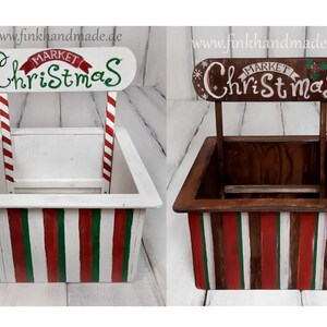 Puede incluir: Dos puestos de mercado navide&ntilde;o de madera con los lados a rayas rojas y verdes. Los puestos est&aacute;n pintados de blanco y tienen un letrero que dice "Mercado de Navidad".