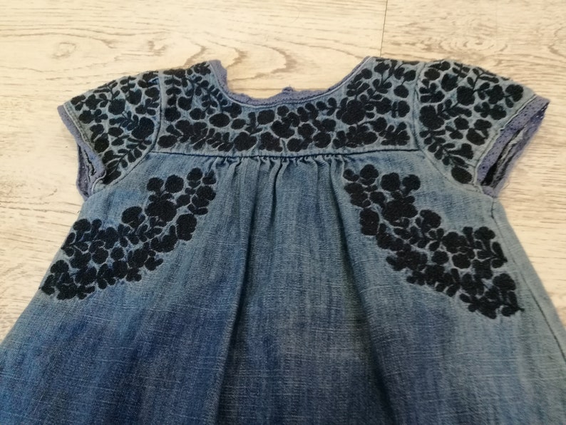 at the front with wrinkles,healthy with botton closure on the back embroidery with small sleeves about 1 year Denim dress little girl