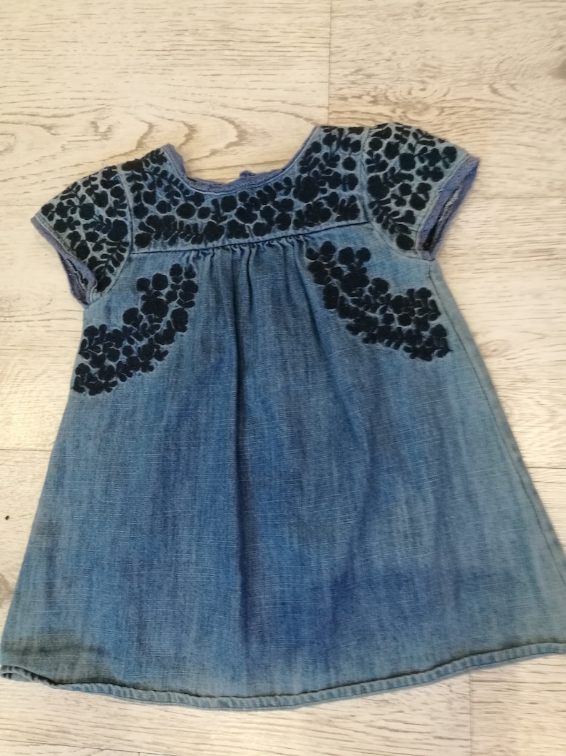 at the front with wrinkles,healthy with botton closure on the back embroidery with small sleeves about 1 year Denim dress little girl