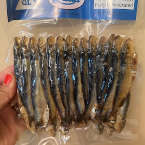 以下が含まれることがあります： 真空パックされたプラスチック包装に入った乾燥塩漬けニシンで、ラベルには「Lucia Dried Salted Herring (Tunsoy) Fully Eviscerated」と記載され、上部の青と白のラベルには正味重量200gと明記されています。