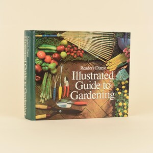 May include: A hardcover book titled Reader's Digest Illustrated Guide to Gardening. The cover features a photographic collage of garden tools, including a rake, trowel, and shears, alongside fresh produce like asparagus, tomatoes, and apples.