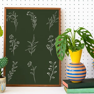 May include: A green chalkboard with white line drawings of various floral and leafy designs. The chalkboard is framed in wood and is leaning against a white wall with black polka dots. There are three vases with plants in front of the chalkboard.
