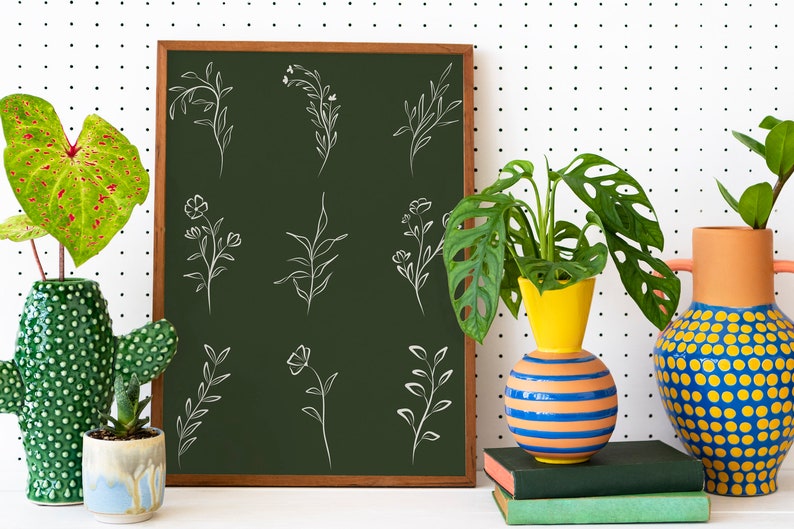 May include: A green chalkboard with white line drawings of various floral and leafy designs. The chalkboard is framed in wood and is leaning against a white wall with black polka dots. There are three vases with plants in front of the chalkboard.