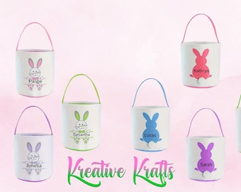May include: Seven personalized Easter baskets with bunny designs and different colored handles. The baskets are white with a bunny design and the names Paige, Michael, Amelia, Samantha, Lucas, Sarah, and Moises are printed on the front. The text "Kreative Krafts" is printed below the baskets.
