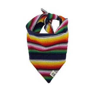 May include: A triangular pet bandana featuring a vibrant, multi-colored striped pattern in shades of red, orange, yellow, green, and pink, set against a dark navy blue background. The fabric is tied at the top and includes a small white label.