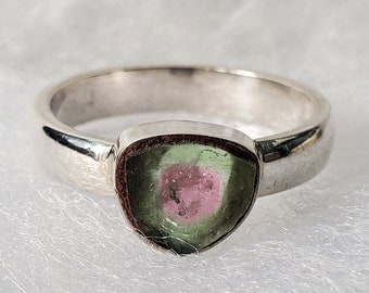 Può includere: Un anello d'argento con una pietra preziosa triangolare verde e rosa.
