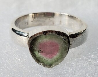 Può includere: Un anello d'argento con una pietra preziosa rosa, verde e bianca incastonata al centro.