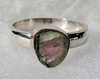 Può includere: Un anello d'argento con una pietra preziosa triangolare verde e rosa.