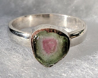 Könnte beinhalten: Ein silberner Ring mit einem grünen, rosafarbenen und weißen Edelstein, der in der Mitte eingesetzt ist.