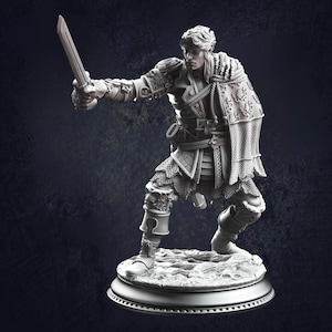 Può includere: Statuetta dettagliata di un guerriero in posa dinamica, con una spada. La figura è vestita con un'armatura ornata con dettagli intricati, tra cui cotta di maglia e motivi decorativi. La base è una piattaforma circolare.