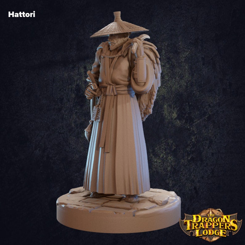 May include: A painted miniature figurine of a man wearing a straw hat and a long robe. He is carrying a large sack on his back and holding a staff in his hand. The figurine is standing on a stone base. The text "The Dragon Trappers Lodge" is visible in the lower right corner of the image.
