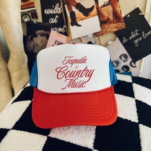 Red, white, and blue foam front trucker hat with red “Tequila & Country Music” text, styled indoors with western-inspired decor.