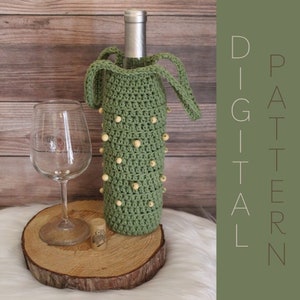 May include: A green crocheted wine bottle holder with wooden beads. The holder has two straps for carrying. The holder is sitting on a wooden slice.