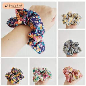 Puede incluir: Una colecci&oacute;n de coleteros florales en varios colores. Un coletero est&aacute; envuelto alrededor de una mu&ntilde;eca, mostrando una tela azul oscuro con flores naranjas, amarillas y rosas. Otros coleteros presentan estampados florales amarillos, azules, rosas y verdes.