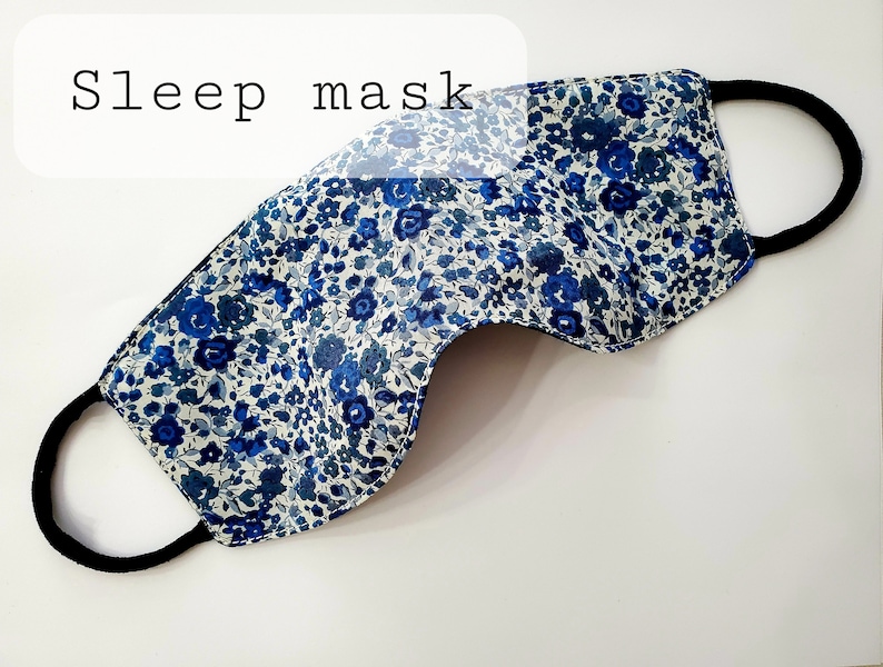 K&ouml;nnte beinhalten: Eine blaue und wei&szlig;e Blumen-Schlafmaske mit einem schwarzen Gummiband.