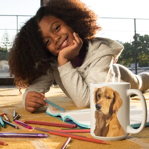 Puede incluir: Una taza de cer&aacute;mica blanca con una ilustraci&oacute;n colorida de un perro golden retriever. La taza est&aacute; sobre una mesa con un libro y l&aacute;pices de colores.