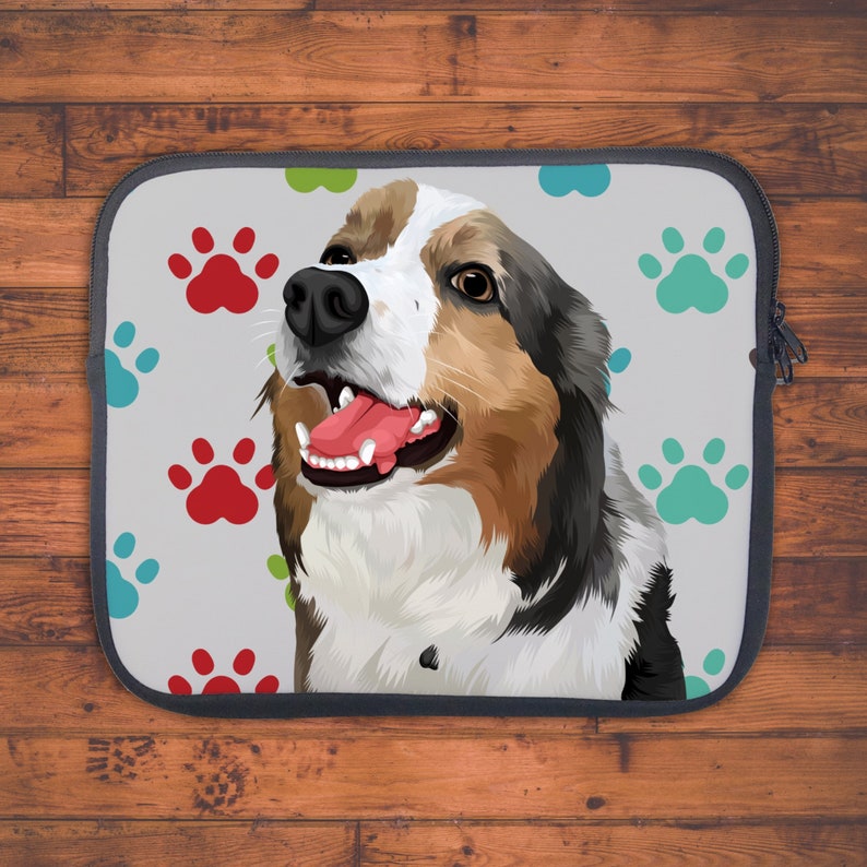 May include: A laptop sleeve with a colorful paw print design. A cartoon dog with brown, white, and black fur is featured on the sleeve. The dog has a happy expression and its tongue is sticking out.