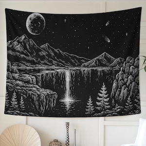 Op de afbeelding: Zwart-wit wandtapijt met een gedetailleerde illustratie van een nachtscène. Het ontwerp bevat een waterval, bergen, bomen, een volle maan, sterren en kometen. Het kunstwerk is een gedetailleerde lijntekening.