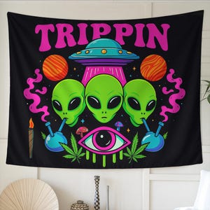 May include: Black tapestry with the word "TRIPPIN" in pink above a design featuring green alien heads, a UFO, planets, and an eye. The aliens are smoking from bongs. The tapestry has a psychedelic theme.