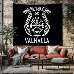 Könnte beinhalten: Schwarzes Wandtuch mit weißer, von Wikingern inspirierter Kunst. Das Design umfasst zwei Drachenköpfe, ein zentrales Symbol und die Worte "VICTORY OR VALHALLA". Das Wandtuch wird an einer Backsteinmauer über einem roten Sofa gezeigt.