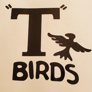 May include: Black graphic of the word "T BIRDS" with a stylized bird silhouette. The letter "T" is large and has quotation marks above it. The image is on a light beige background.
