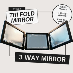 May include: A black tri-fold mirror with three rectangular panels. The mirror has a wood frame and is labeled "STYLEZ TRI FOLD MIRROR" and "3 WAY MIRROR".