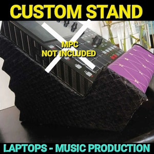 Può includere: Supporto personalizzato nero con parte superiore trapuntata viola. Il supporto è inclinato e progettato per contenere un dispositivo di produzione musicale. Il testo "MPC NOT INCLUDED" è scritto sul supporto. Il supporto è per laptop e produzione musicale.