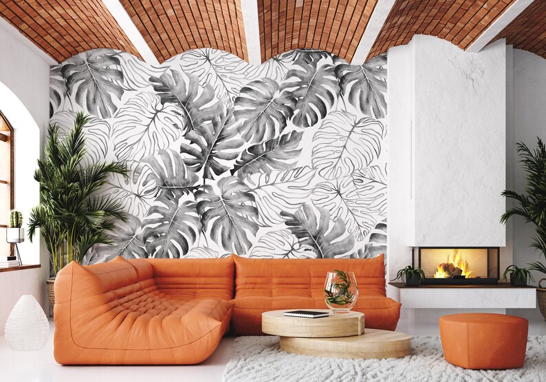 May include: A living room interior with an orange sectional sofa, a coffee table, and a fireplace. The wall behind the sofa is decorated with a black and white tropical leaf wallpaper.