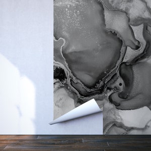 May include: A close-up of a black and white abstract wallpaper being applied to a white wall. The wallpaper has a marbled, fluid design.