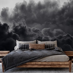 Puede incluir: Una cama con un edredón gris oscuro y una cabecera de madera. La cama está frente a una pared con una foto en blanco y negro de nubes.