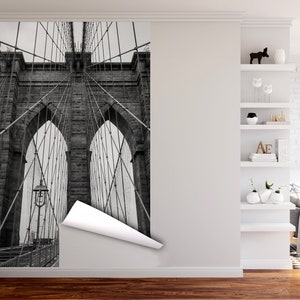 May include: A black and white photograph of the Brooklyn Bridge in New York City. The image shows the bridge's iconic towers and suspension cables.