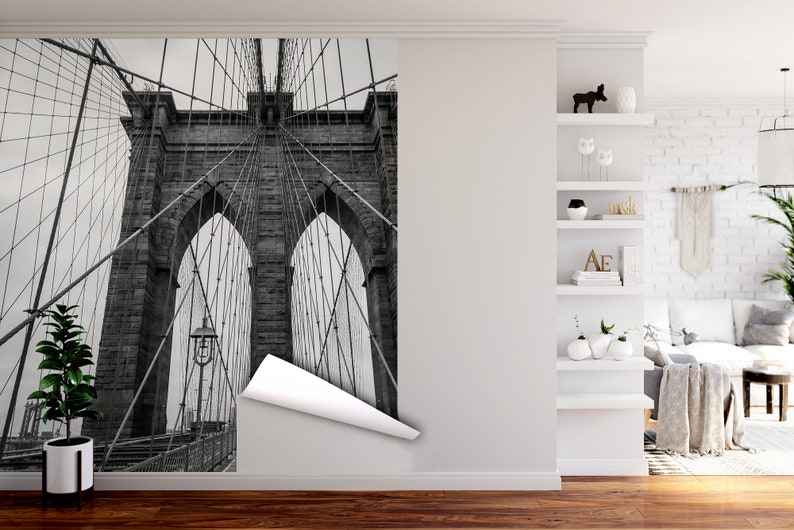 May include: A black and white photograph of the Brooklyn Bridge in New York City. The image shows the bridge's iconic towers and suspension cables.