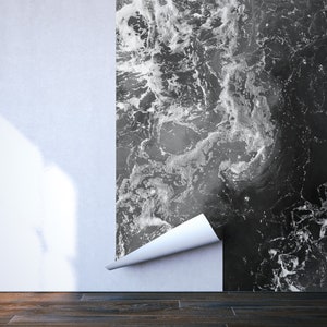 May include: A partially installed wallpaper with a black and white marble design. The wallpaper is peeling away from the wall, revealing a white surface. The floor is made of dark wood.