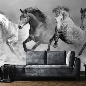 May include: Black and white mural featuring four running horses, creating a dynamic and artistic display. The horses are captured in motion, with flowing manes and a sense of speed. A dark gray sofa and side table are in the foreground.