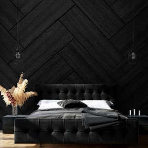 Puede incluir: Una cama tapizada en negro con cabecero negro y una manta negra. La cama está en una habitación con una pared de patrón de espiga negra y una alfombra blanca.
