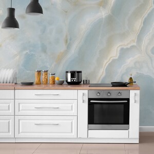 May include: White kitchen cabinets with a stainless steel oven and a black countertop. The backsplash is a light blue and white marble pattern.