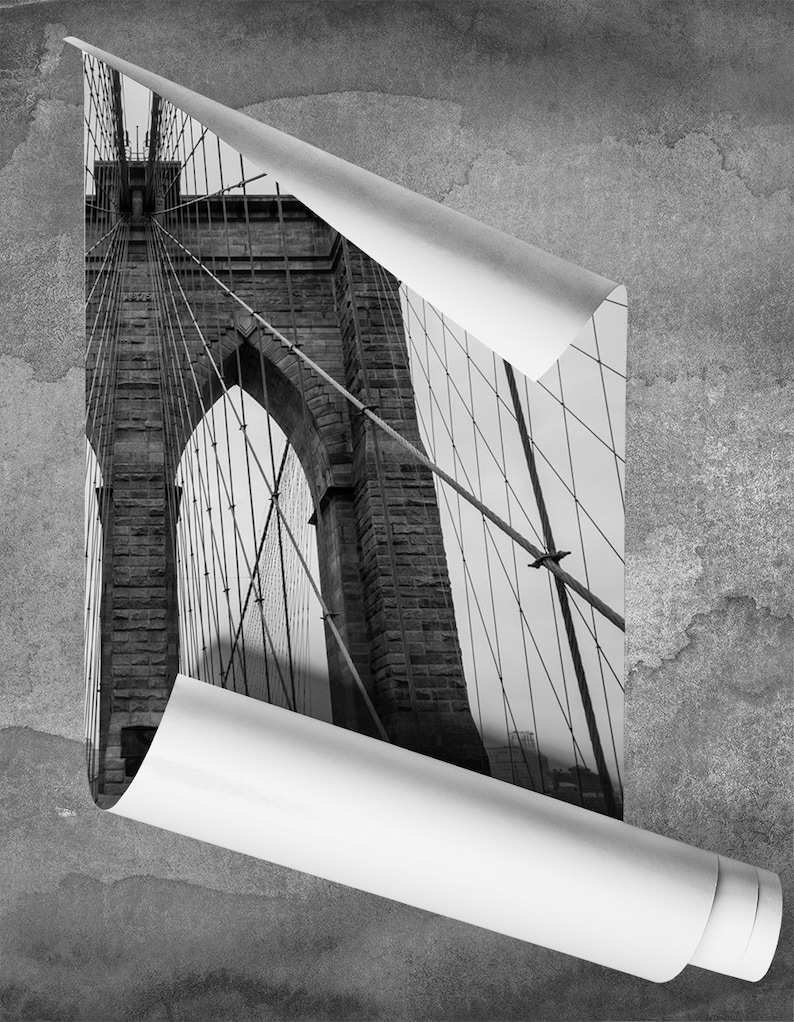 May include: A black and white photograph of the Brooklyn Bridge in New York City. The image is cropped to show the bridge's towers and cables.